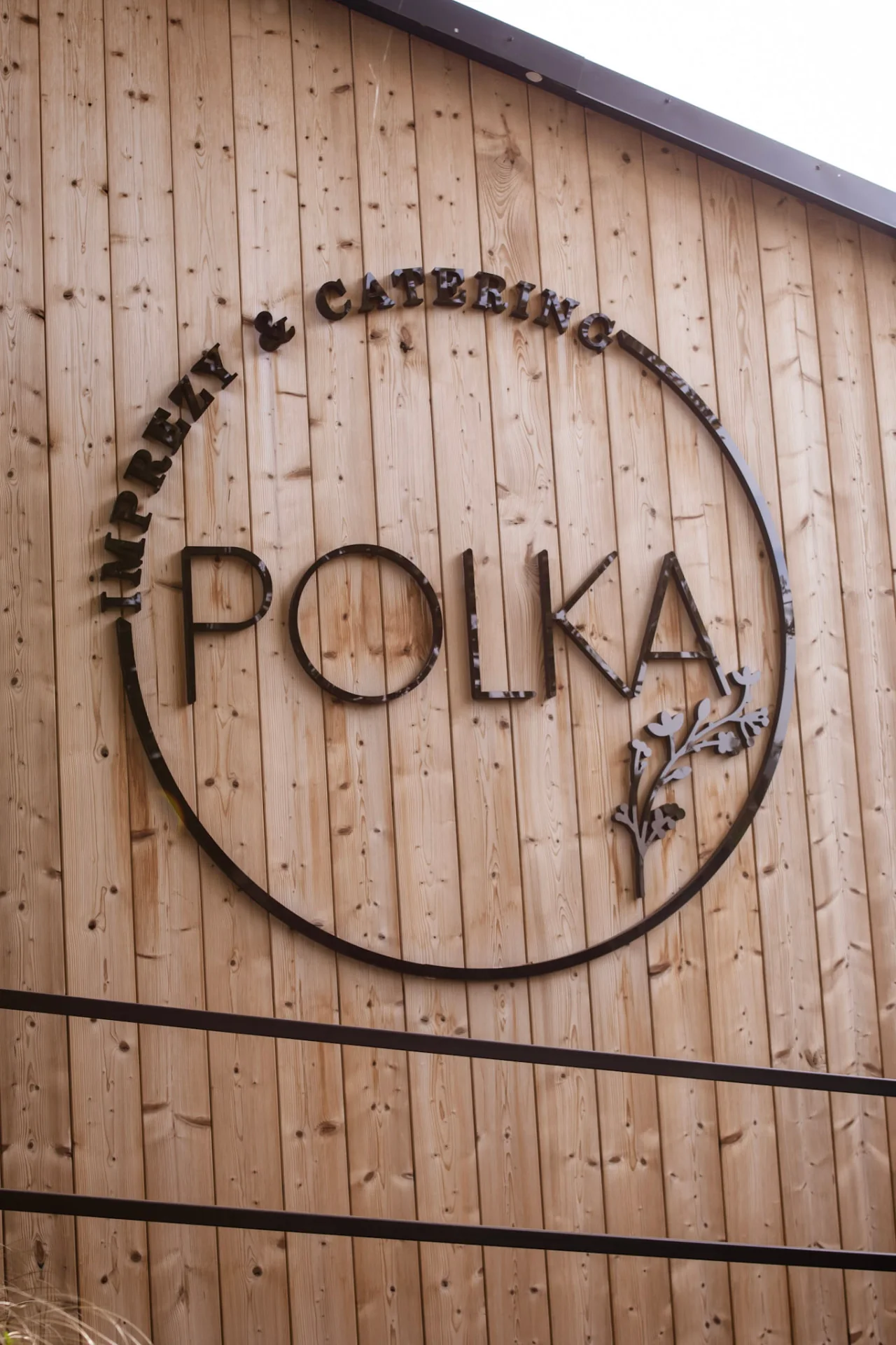 Okrągły szyld Polki na drewnianej elewacji
